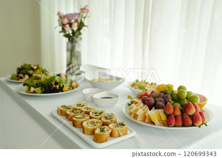 Preparing Vibrant Salad And Fruit Platter With Bread Rolls 120699343