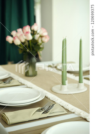 Arranging Elegantly Set Dining Table with Floral Centerpiece 120699375