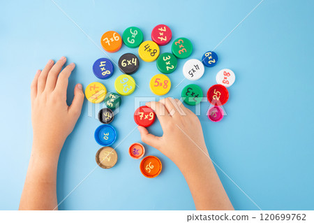 Learn the multiplication tables in an interactive way, free math multiplication learning games for 3rd, 4th grade. bottle caps with multiplication exercises on blue background, practice for kids, 120699762