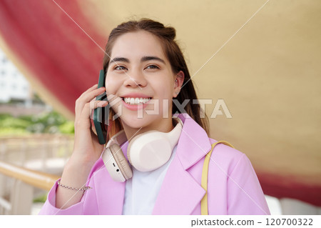 Smiling Woman Holding Smartphone Wearing Headphones Smiling Woman Holding Smartphone Wearing Headphones 120700322