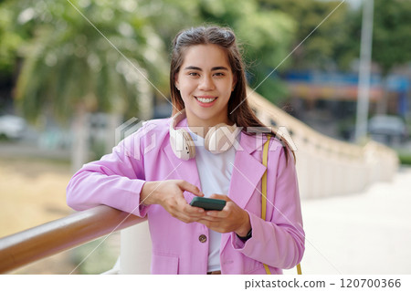 Portrait of Smiling Young Woman Holding Smartphone Outdoors Portrait of Smiling Young Woman Holding Smartphone Outdoors 120700366