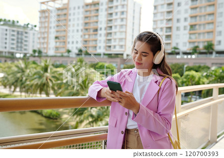 Enjoying Music While Texting in Urban Park 120700393