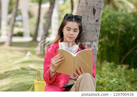 Reading Book Under Tree With Sunglasses and Headphones 120700416