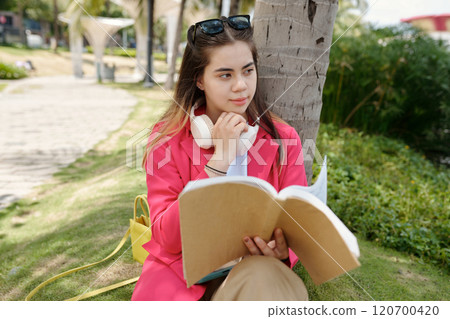 Reading a Book while Sitting on Park Bench 120700420