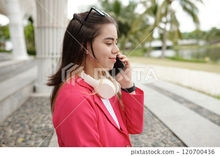 Smiling Woman Engaging in Phone Conversation Outside 120700436