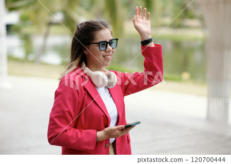 Waving Hand While Holding Smartphone Outdoors Waving Hand While Holding Smartphone Outdoors 120700444