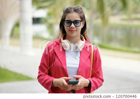 Smiling Woman Wearing Sunglasses and Holding Smartphone 120700446