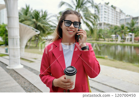Smiling Woman Holding Coffee Wearing Pink Blazer Outdoors 120700450