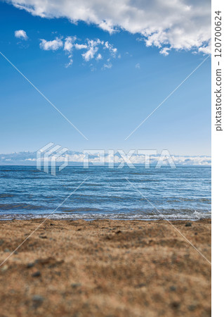 Sandy beach, Issyk-Kul Lake, Mountains in clouds, Sun rays, summer Kyrgyzstan 120700624