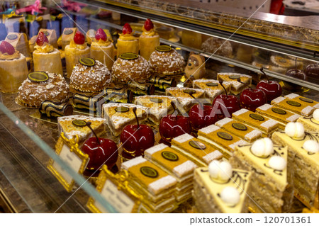 Variety of cakes and candied cherries in display case of an expensive pastry shop 120701361