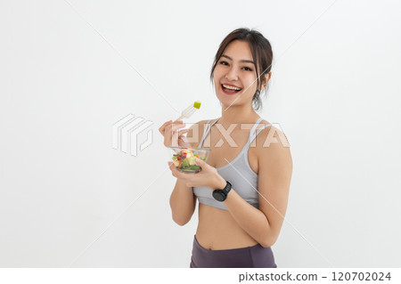 Asian attractive lady sportswear healthy eating salad vegetables over white background. Female holding salad bowl various vegetables and fruit healthy food for weight loss and exercise. 120702024