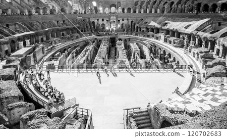 Visitors admire the intricate design of the Colosseum's interior in Rome, showcasing ancient architecture and historical significance during a sunny day. 120702683