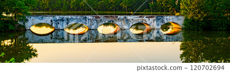The historic stone inundation bridge spans Vitek Pond, reflecting in the still water as evening light enhances the serene atmosphere of South Bohemia's Trebon Pond System. 120702694