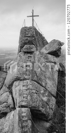 A wooden summit cross stands atop the Oresnik granite formation in Hejnice, Jizera Mountains, offering stunning views of the surrounding landscape and a unique hiking experience. 120702775
