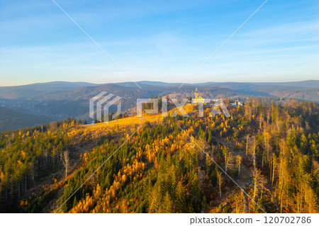 The Tanvaldsky Spicak Lookout Tower stands tall amidst the colorful foliage of the Jizera Mountains during a serene autumn evening. The Tanvaldsky Spicak Lookout Tower stands tall amidst the colorful foliage of the Jizera Mountains during a serene autumn evening. 120702786