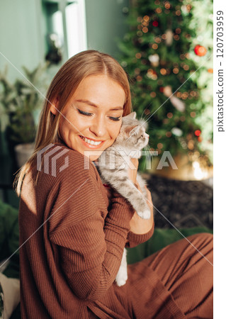 A beautiful woman at home near the Christmas tree 120703959