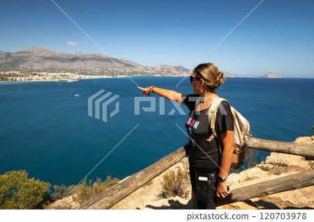 Girl with backpack looking at the sea Girl with backpack looking at the sea 120703978