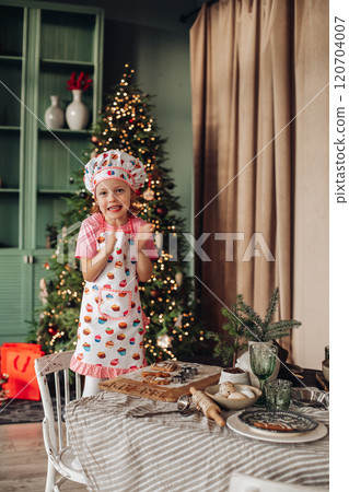 a girl child in the kitchen with a Christmas tree 120704007