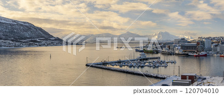 Norwegian city of Tromso in the winter. Snowy roofs, embankment near the port and fishing ships, Sunny winter day. Norwegian city of Tromso in the winter. Snowy roofs, embankment near the port and fishing ships, Sunny winter day. 120704010