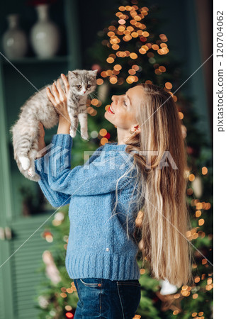 A beautiful woman at home near the Christmas tree 120704062