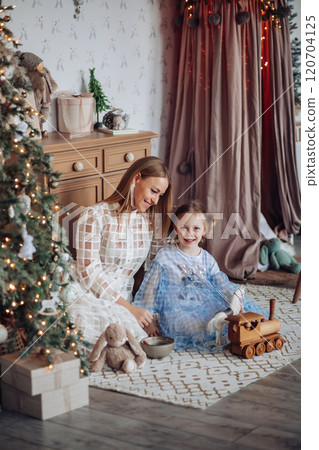 Smiling girl with mom near christmas tree at home Smiling girl with mom near christmas tree at home 120704125