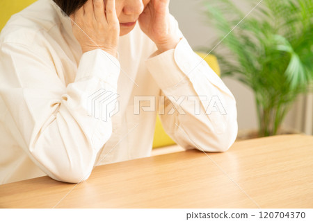 中高級婦女在客廳抱著頭 中高級婦女在客廳抱著頭 120704370