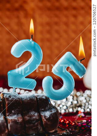 lit candles forming number 25 on a cake 120706527