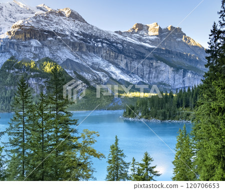 Idyllic morning view of the lake Oeschinensee. Location Swiss alps, Switzerland, Kandersteg district. Blue mountain lake with pine trees and mountains in background. Idyllic morning view of the lake Oeschinensee. Location Swiss alps, Switzerland, Kandersteg district. Blue mountain lake with pine trees and mountains in background. 120706653