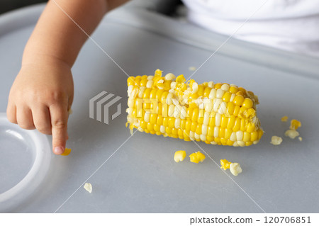 Baby picking sweet corn kernels from the table. Closeup. Baby picking sweet corn kernels from the table. Closeup. 120706851