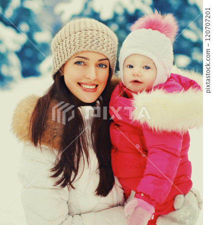 Winter portrait happy smiling mother and baby on hands over snowy christmas tree background Winter portrait happy smiling mother and baby on hands over snowy christmas tree background 120707201
