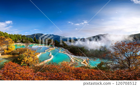 Huanglong National Park, showcasing the vibrant turquoise pools, golden autumn foliage, and misty mountain ranges under a clear blue sky, UNESCO World Heritage Site in Sichuan, China, AI-generated  120708512