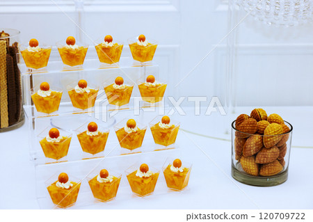 Refined dessert arrangement showcases small cups filled with cream topped by orange sweets cookies perfect for celebratory occasions. 120709722