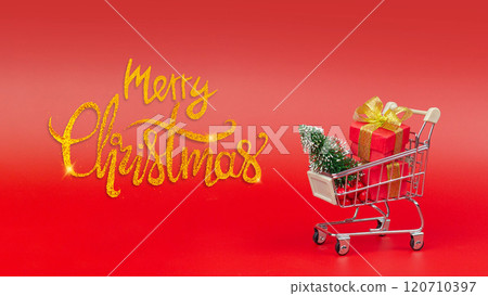 Merry Christmas inscription and a trolley with gifts and a Christmas tree. Buying gifts, preparing for the holidays banner Merry Christmas inscription and a trolley with gifts and a Christmas tree. Buying gifts, preparing for the holidays banner 120710397