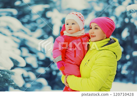 Winter portrait happy mother holds baby on hands over snowy christmas tree background 120710428
