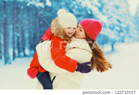 Winter happy smiling mother hugging kissing child over snowflakes background Winter happy smiling mother hugging kissing child over snowflakes background 120710557