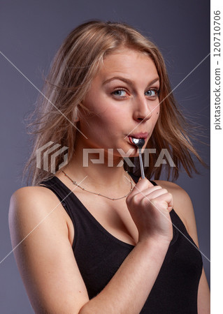 woman with a spoon in mouth 120710706