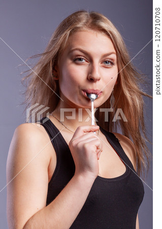 woman with a spoon in mouth woman with a spoon in mouth 120710708