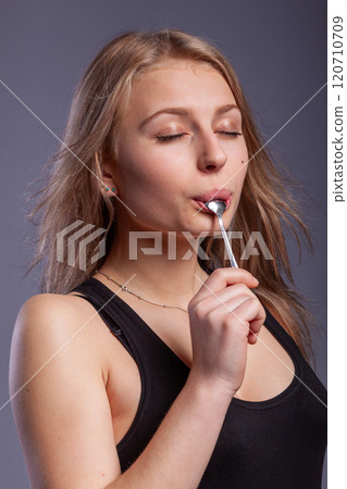 woman with a spoon in mouth 120710709