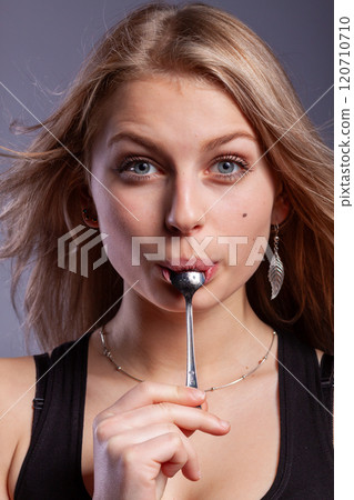 woman with a spoon in mouth 120710710