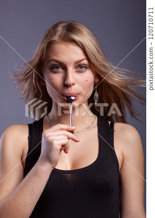 woman with a spoon in mouth 120710711