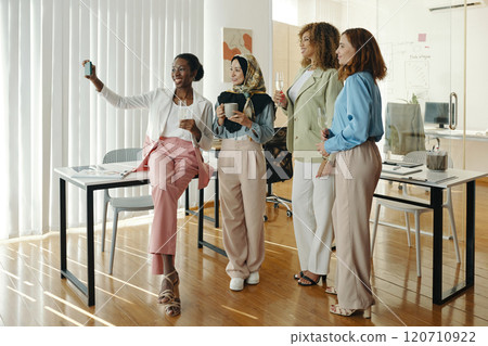 Four Colleagues Taking a Group Selfie in Office Setting 120710922