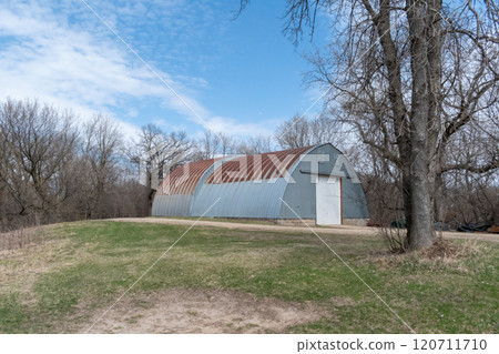 Rustic Quonset in Serene Countryside with Clear Blue Sky and Surrounding Trees. Rustic Quonset in Serene Countryside with Clear Blue Sky and Surrounding Trees. 120711710
