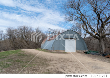Rustic Quonset in Serene Countryside with Clear Blue Sky and Surrounding Trees. Rustic Quonset in Serene Countryside with Clear Blue Sky and Surrounding Trees. 120711711