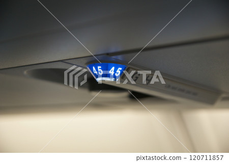 Above the Clouds, November 24, 2018: Seat Row Display and No Smoking Sign on the Ceiling of a Long-Haul Airplane 120711857