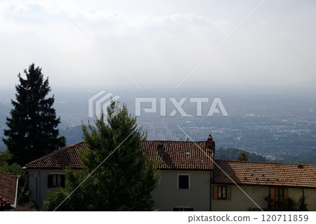 Turin, Italy, September 14, 2019: Mountain View with Traditional Italian House, Red Roof, and Hazy Cityscape in the Valley 120711859