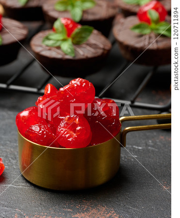Candied red cherries in a copper bowl on a table Candied red cherries in a copper bowl on a table 120711894