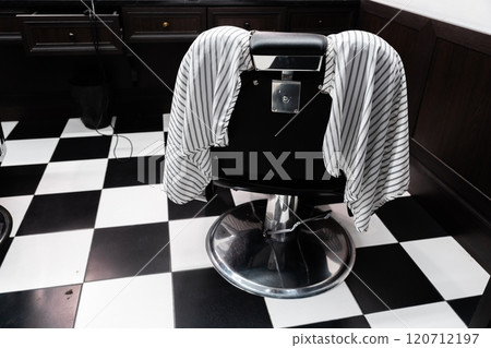 Barber chair with striped cape waiting for client in modern salon Barber chair with striped cape waiting for client in modern salon 120712197