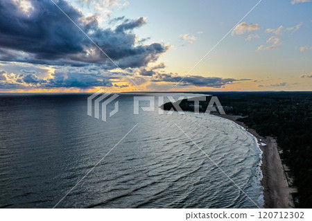 Serene sunset over a calm lake with gentle waves and distant shoreline in the twilight hours of a summer evening Serene sunset over a calm lake with gentle waves and distant shoreline in the twilight hours of a summer evening 120712302