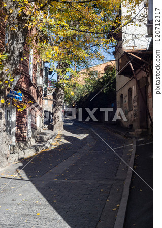 Beautiful autumn leaves line the cobblestone streets of Tbilisi, Georgia, capturing a moment of serene tranquility 120712317