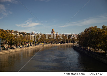 Golden autumn hues reflect in the tranquil waters of Tbilisi, showcasing the beauty of nature and architecture Golden autumn hues reflect in the tranquil waters of Tbilisi, showcasing the beauty of nature and architecture 120712323